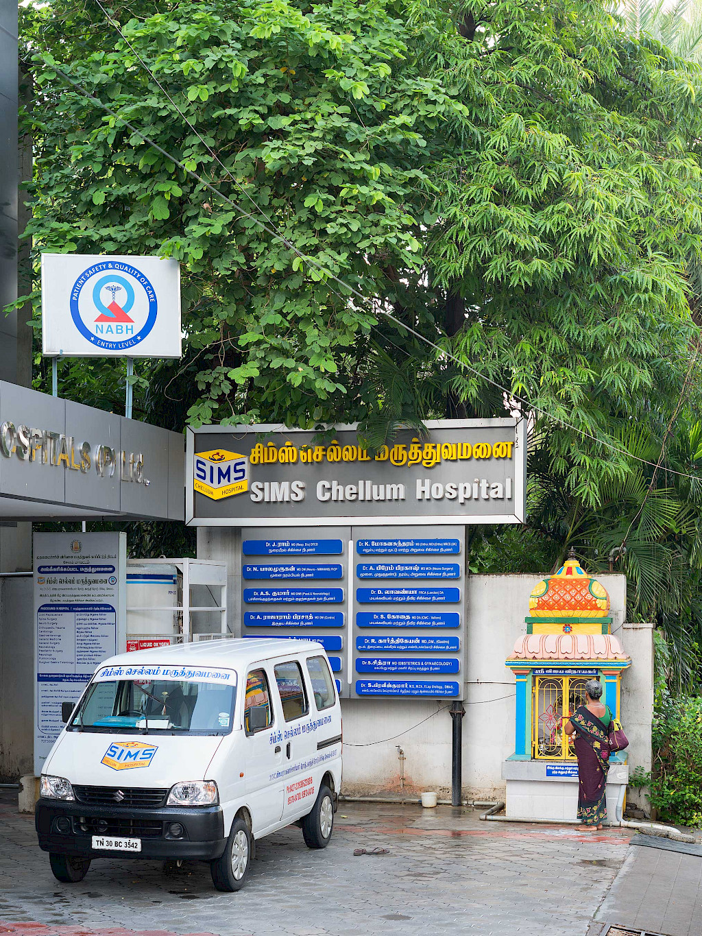 Entrance area of the Sims Chellum Hospital: A woman stands in front of a colorful shrine.