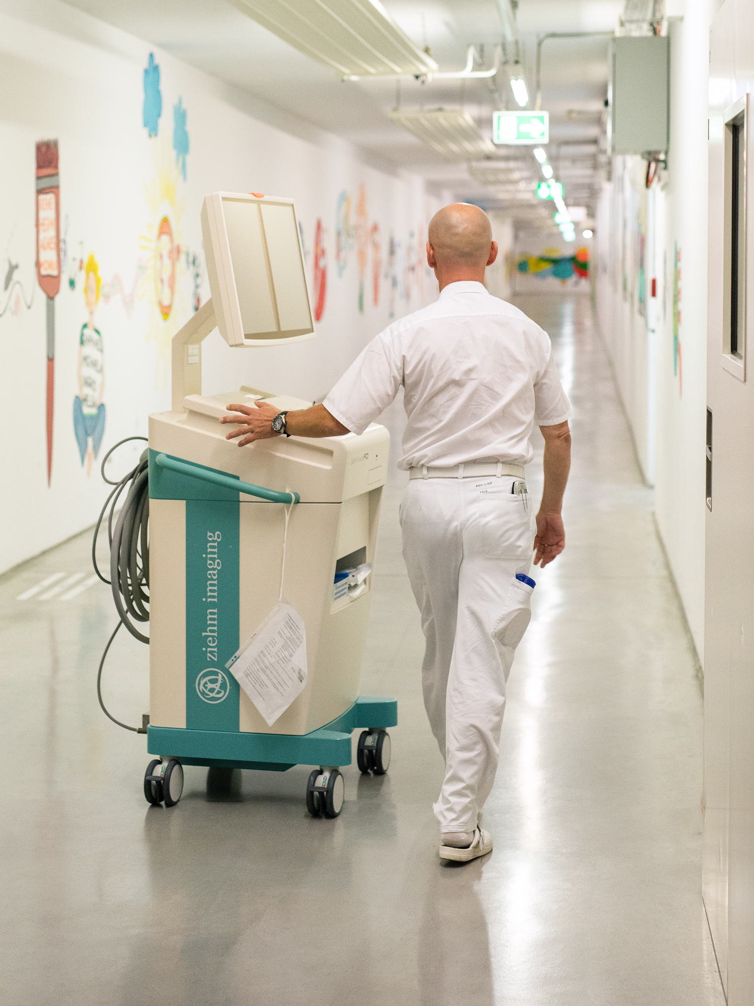 Engineer Norbert Lechner pushes a Ziehm Imaging monitor cart through a corridor at Kepler University Hospital in Linz, Austria.