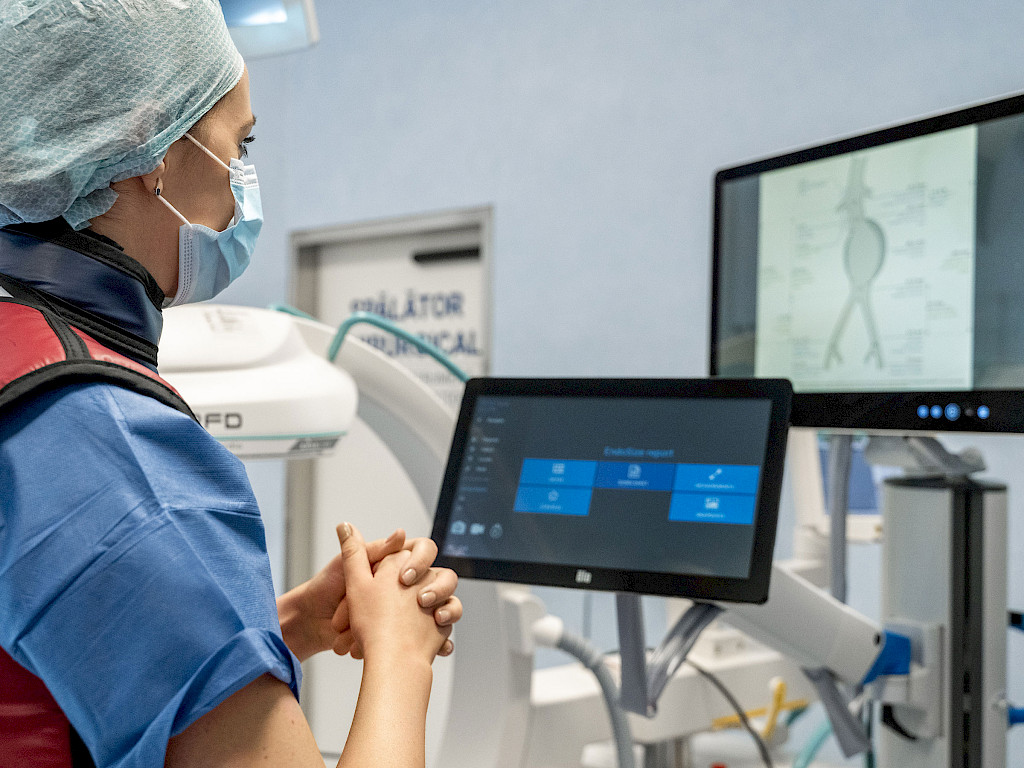 Andrea Costache stands in front of a screen displaying images and data for planning an endovascular aortic repair (EVAR) procedure