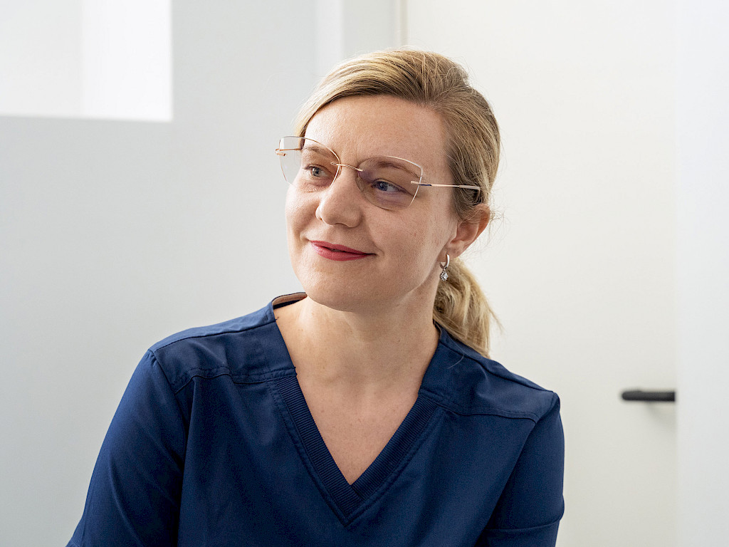 Portrait of Dr. Anca Chitic, a blonde female doctor wearing blue surgical attire
